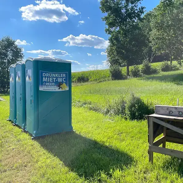 Drei Toilettenkabinen auf einer Wiese
